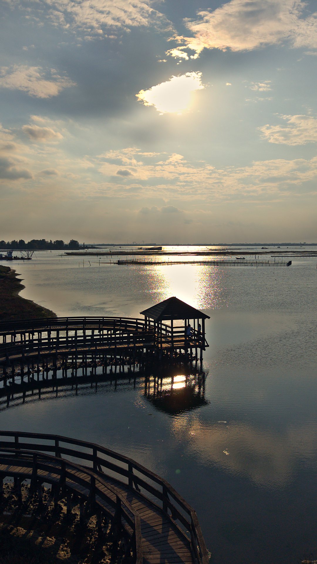Pontile in legno sulla laguna del Delta del Po al tramonto, ripreso dal drone
